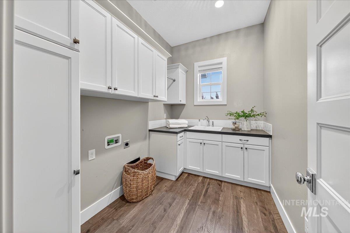 Washroom with cabinet space, hookup for a washing machine, dark wood-type flooring, and electric dryer hookup