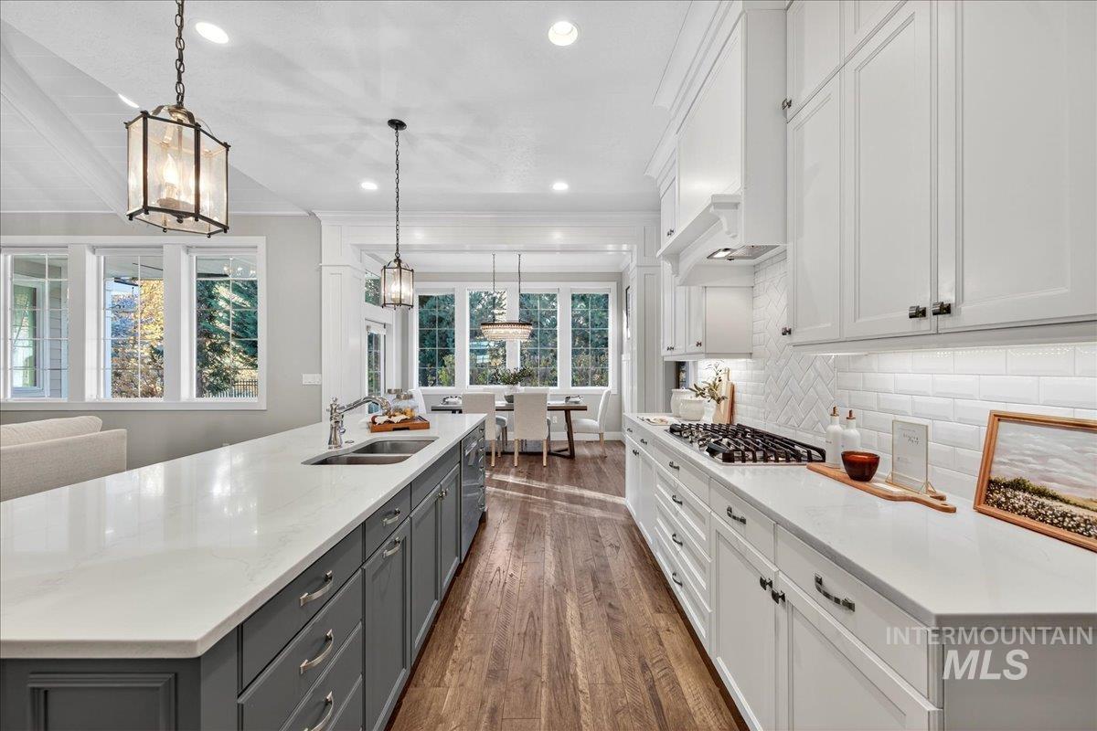 Kitchen with white cabinetry, gray cabinetry, pendant lighting, dark wood finished floors, and decorative backsplash