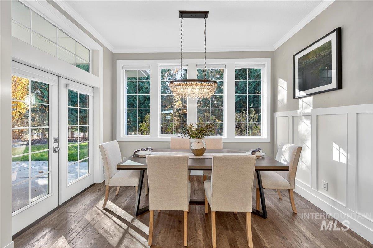 Dining space featuring dark wood-style floors, french doors, a decorative wall, plenty of natural light, and wainscoting