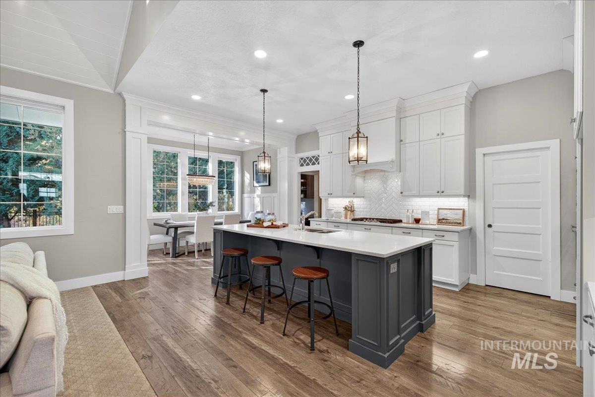 Kitchen with a kitchen breakfast bar, pendant lighting, white cabinets, gray cabinetry, and light wood-type flooring
