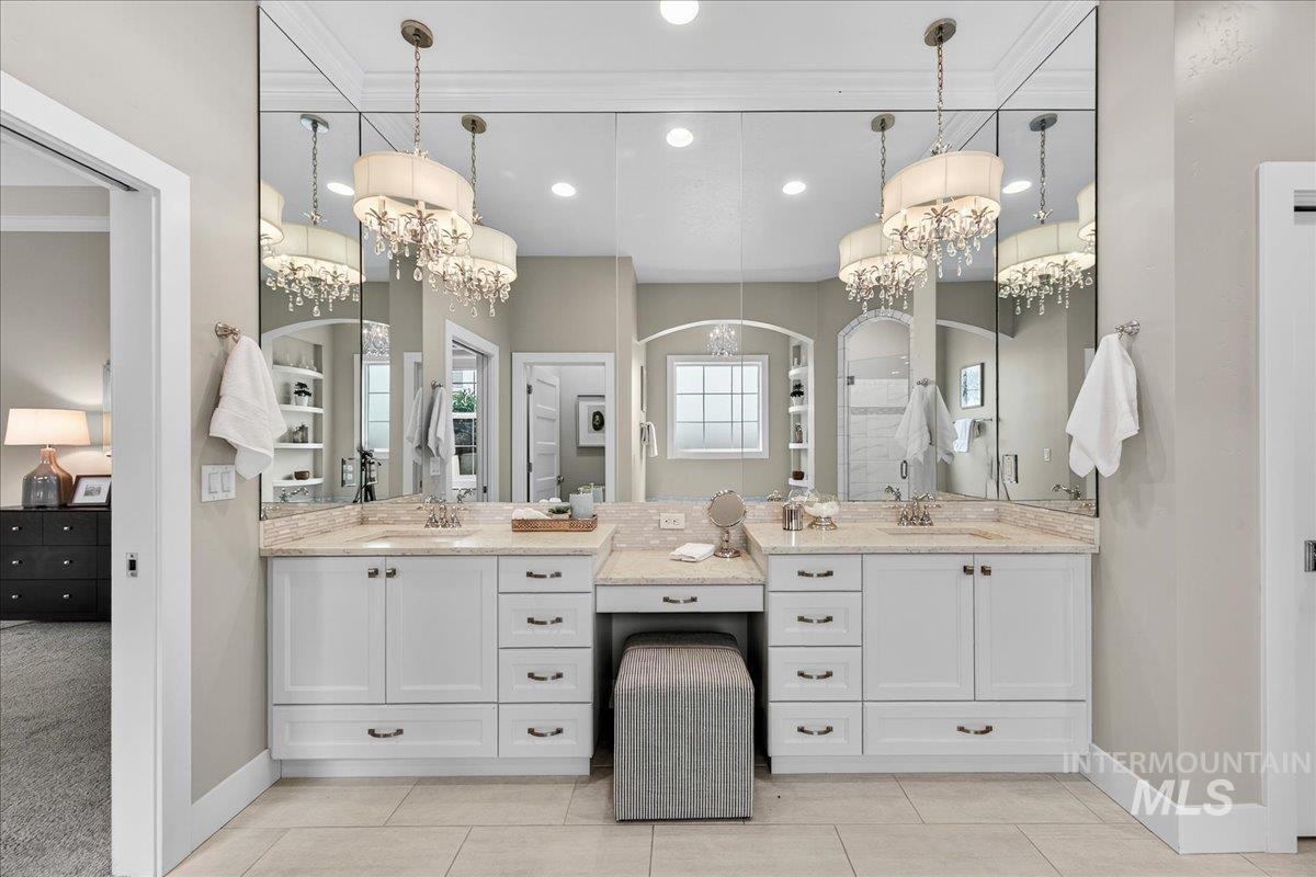 Full bathroom with a chandelier, double vanity, a stall shower, crown molding, and light tile patterned flooring