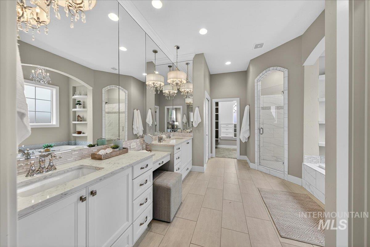 Full bath featuring a spacious closet, a chandelier, a shower stall, two vanities, and built in features
