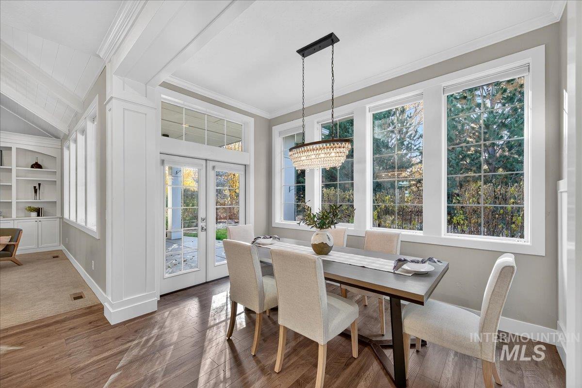 Dining area featuring french doors, hardwood / wood-style flooring, a chandelier, ornamental molding, and built in shelves