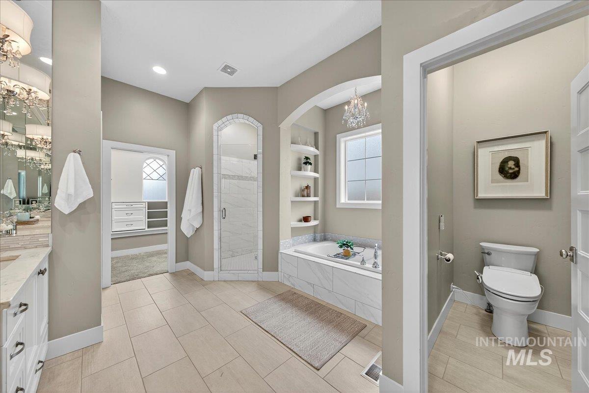 Bathroom with vanity, a garden tub, a chandelier, a stall shower, and built in shelves
