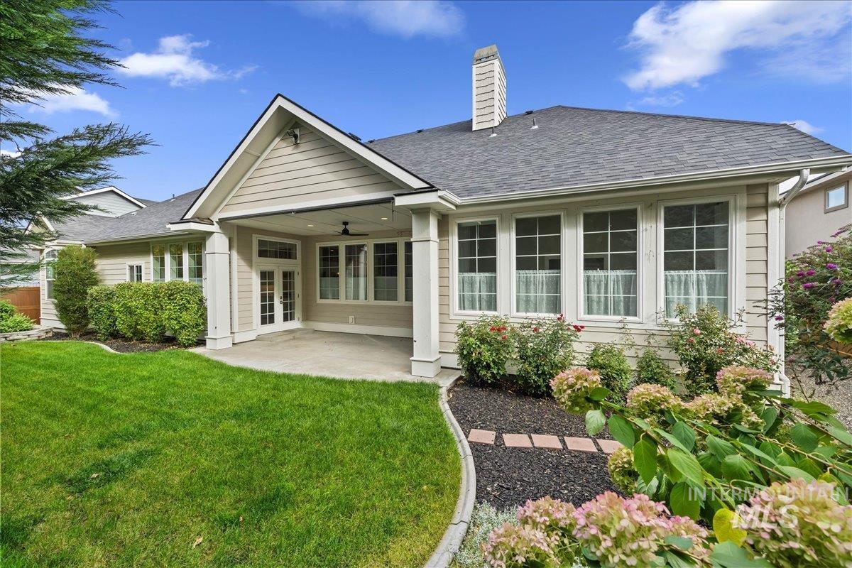 Rear view of house featuring a ceiling fan, a patio area, a chimney, and a shingled roof