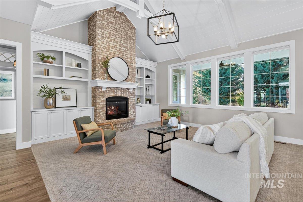 Living room featuring healthy amount of natural light, a fireplace, a chandelier, and built in features