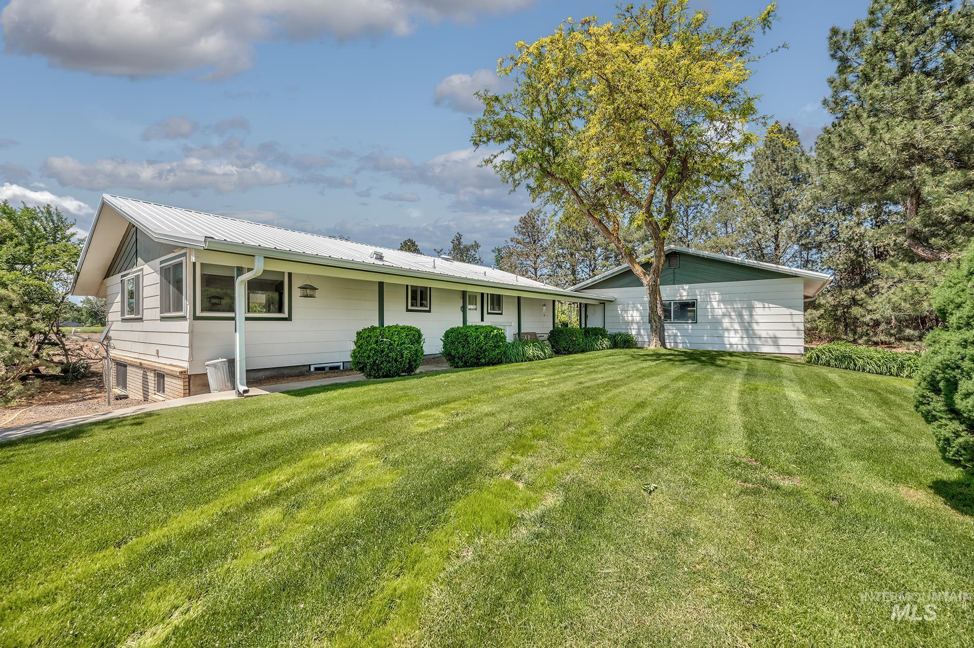 White siding exterior with a metal roof and green trim