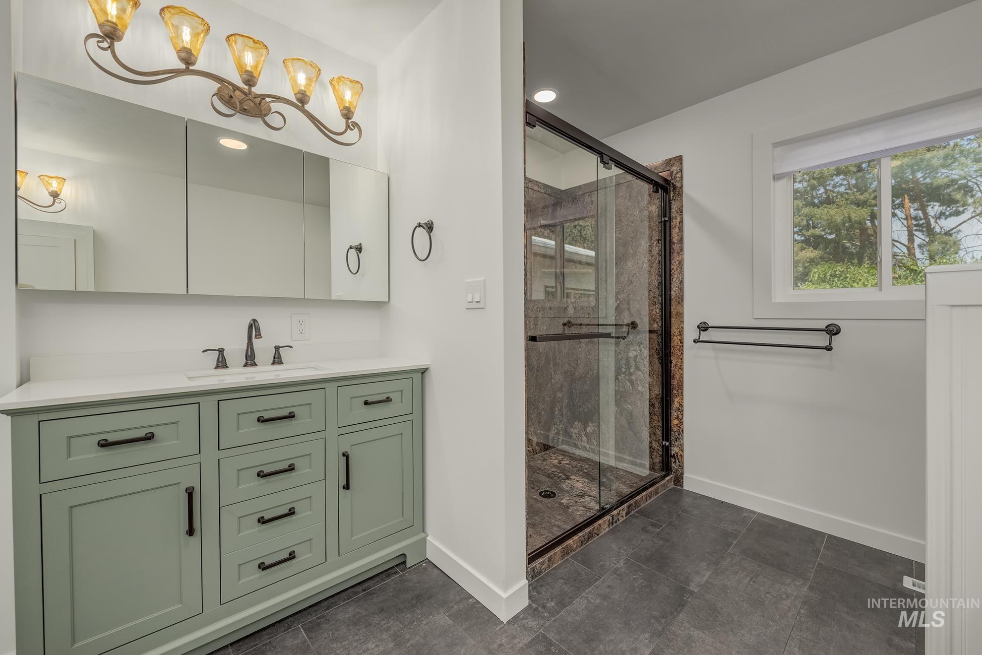 Bathroom featuring a sage green vanity with black hardware, white countertop, and a built-in sink