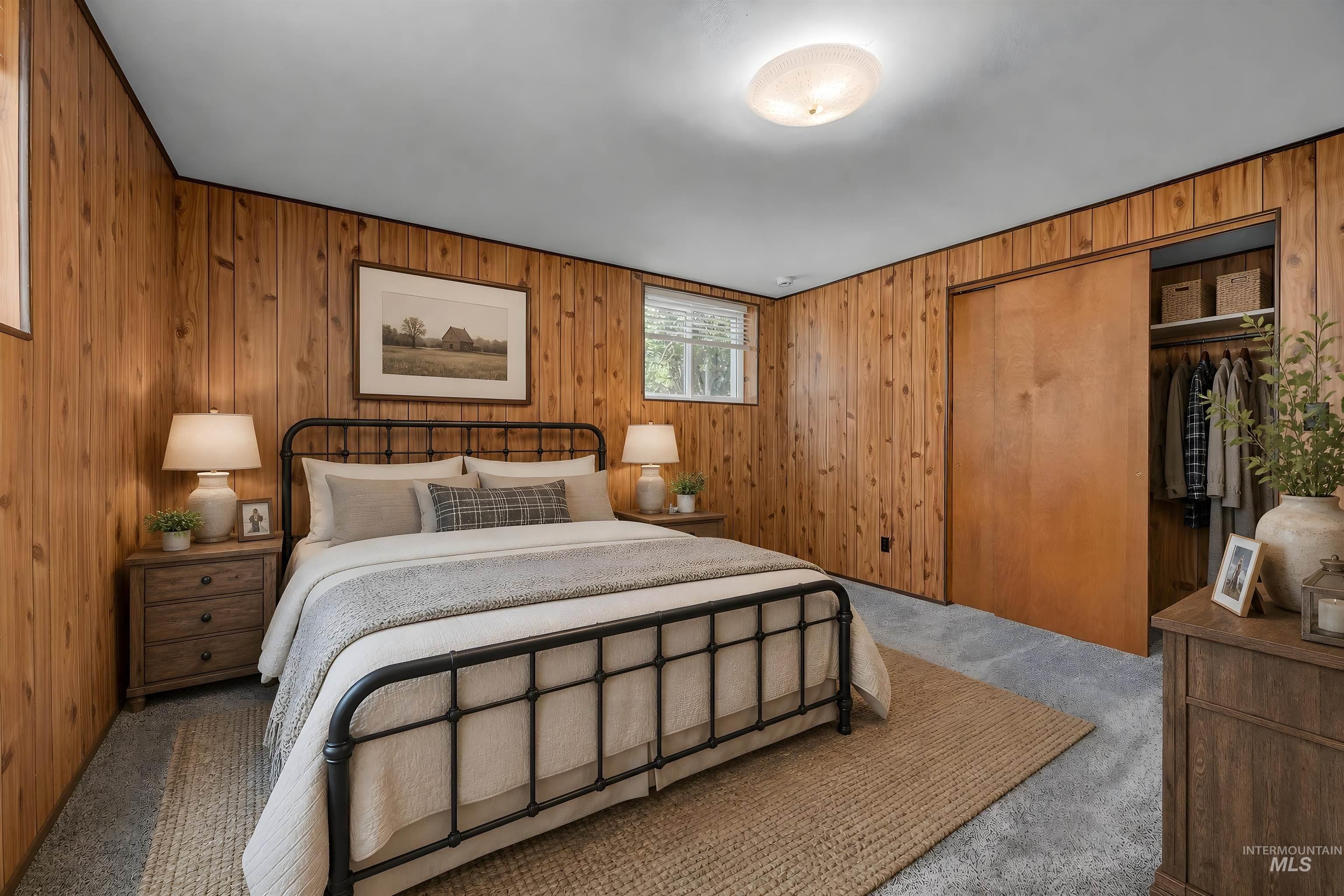 Wood-paneled room featuring light gray carpeting and a built-in closet with sliding wood doors