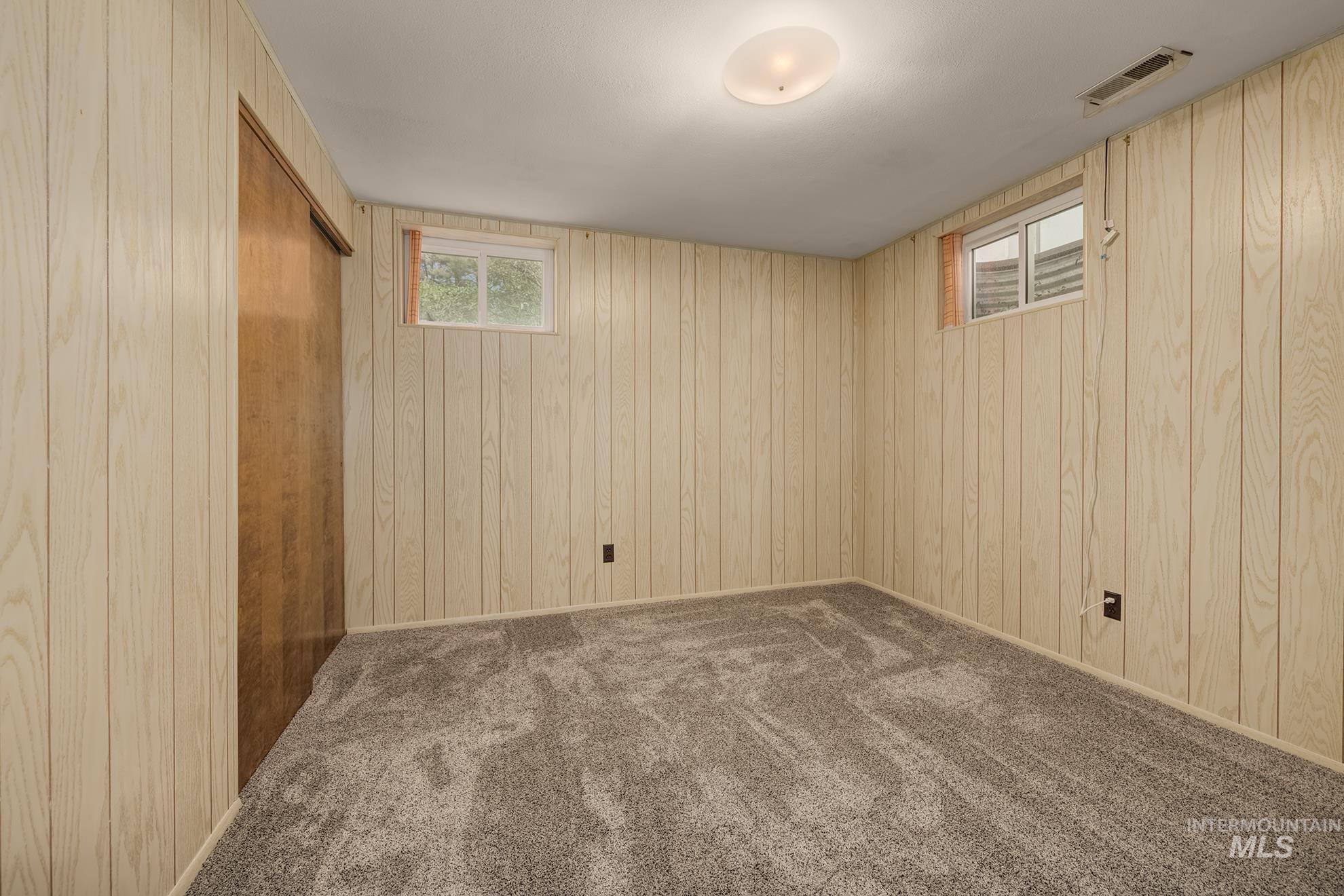 Room featuring light wood-finish paneled walls and grey carpet