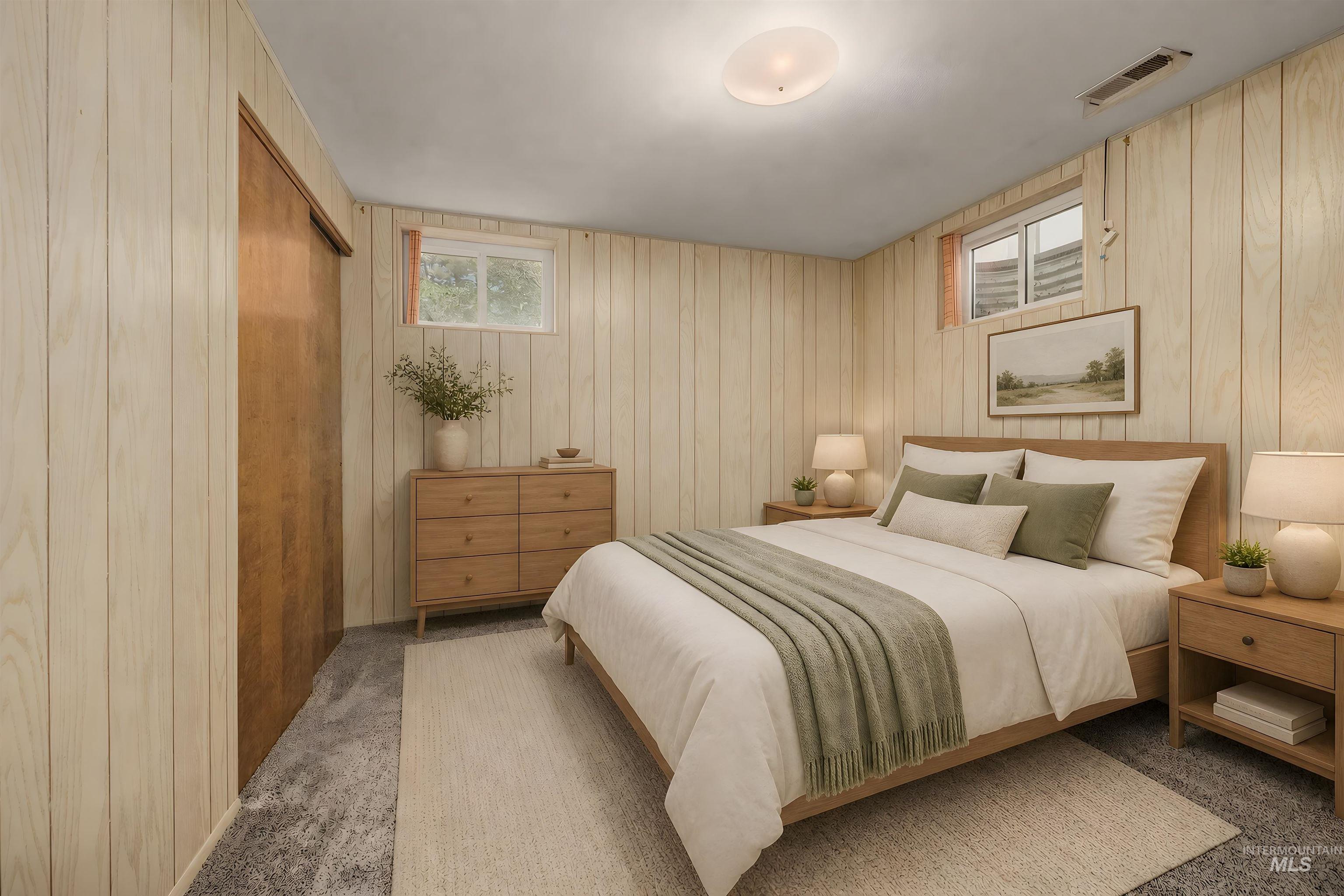 Bedroom featuring vertical wood paneling, a large sliding wood closet door, and two windows