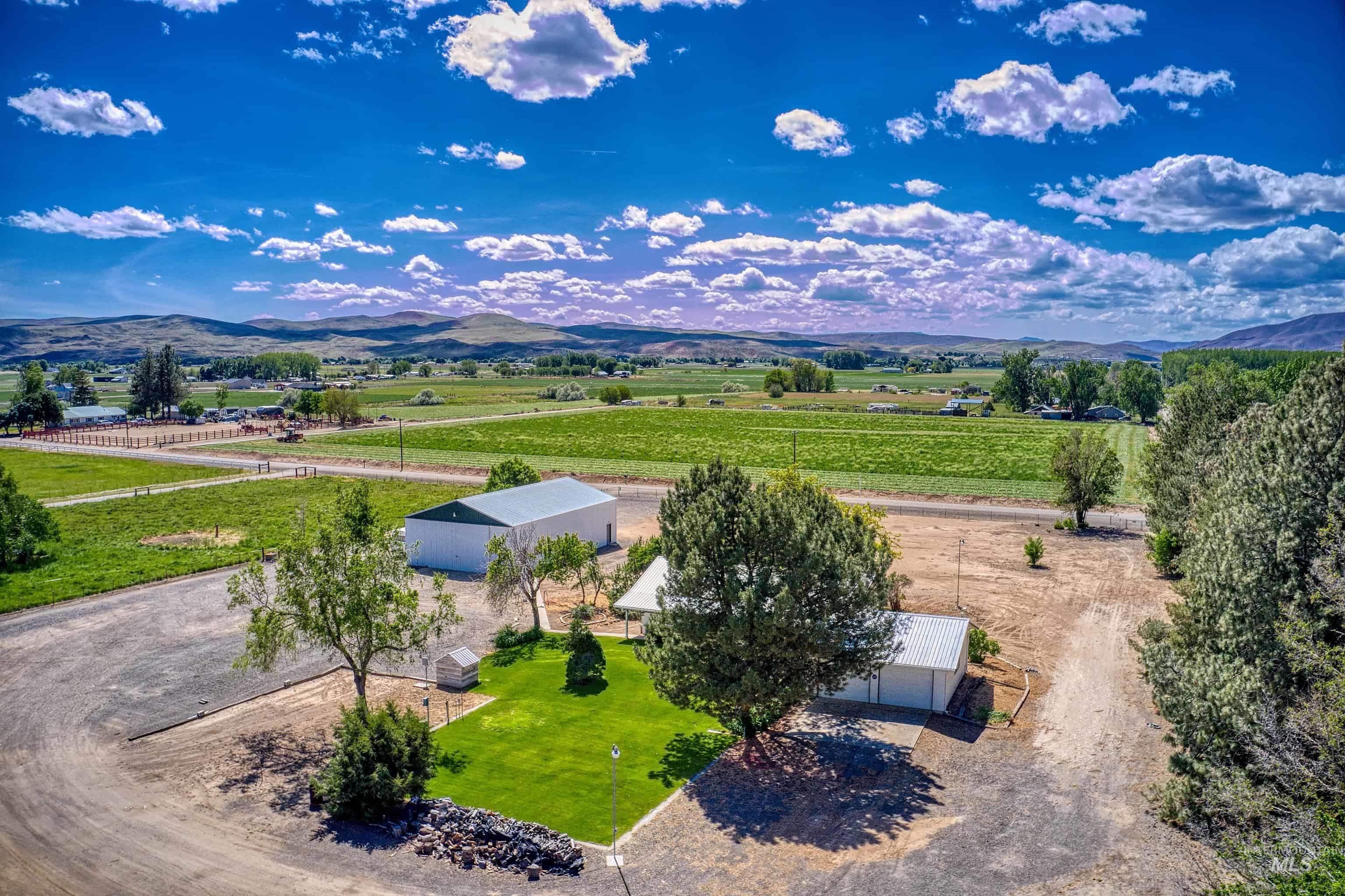 Expansive property featuring a large metal-sided outbuilding, a secondary white outbuilding, and a verdant lawn area
