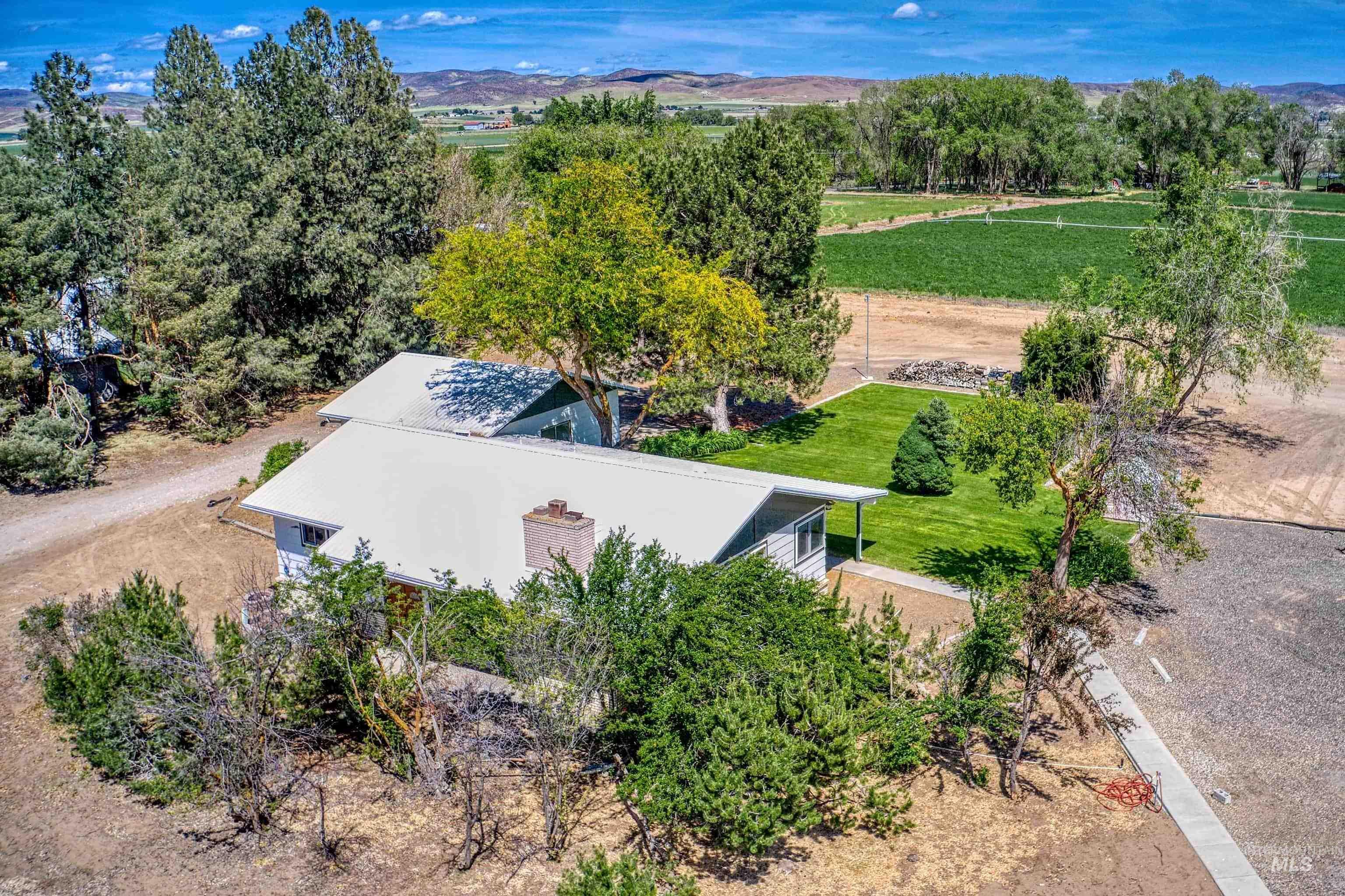 Rural property featuring a single-story residence with a metal roof and a brick chimney