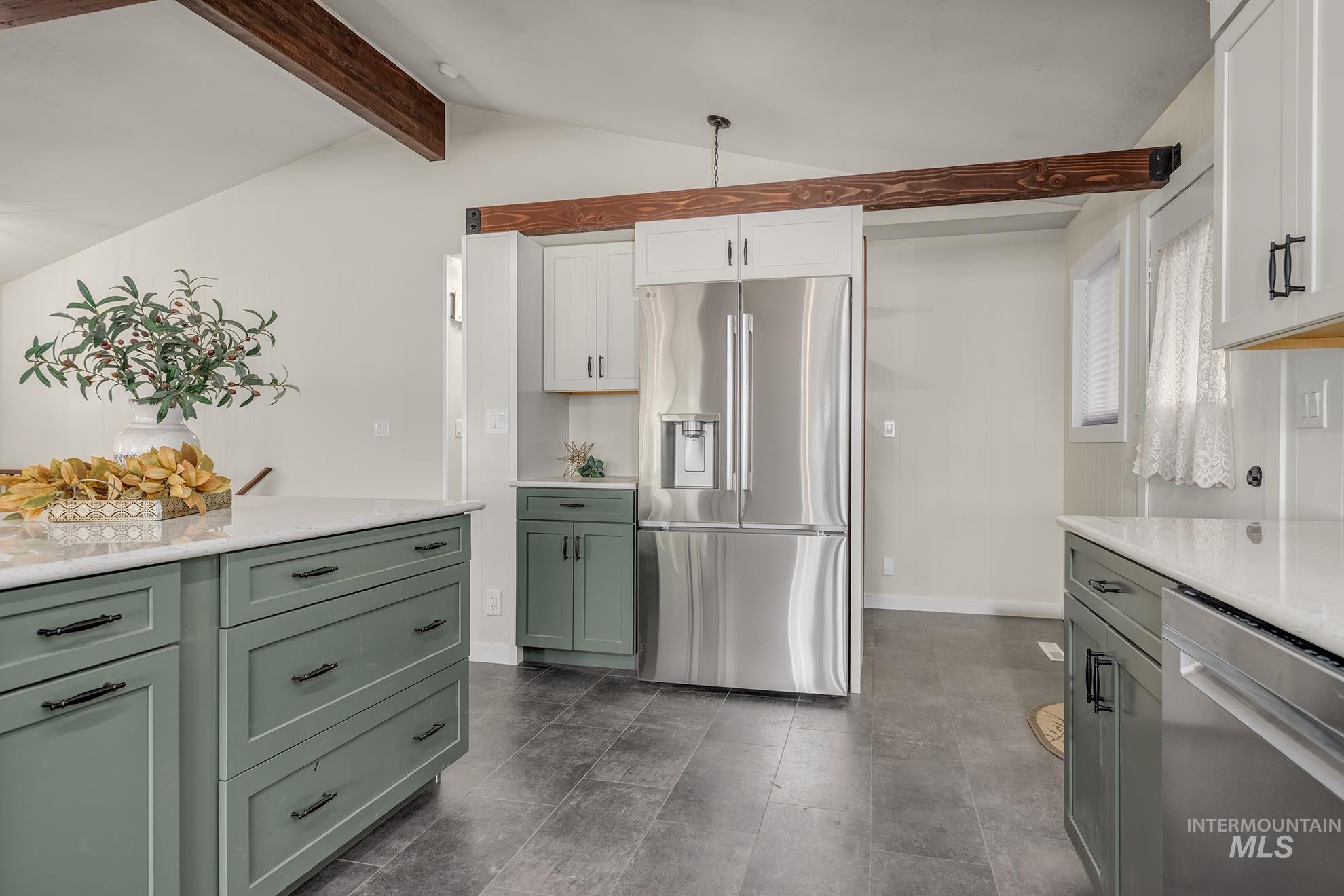 Kitchen featuring a stainless steel refrigerator, white countertops, two-tone cabinetry, wood-look ceiling beams, and dark tile flooring