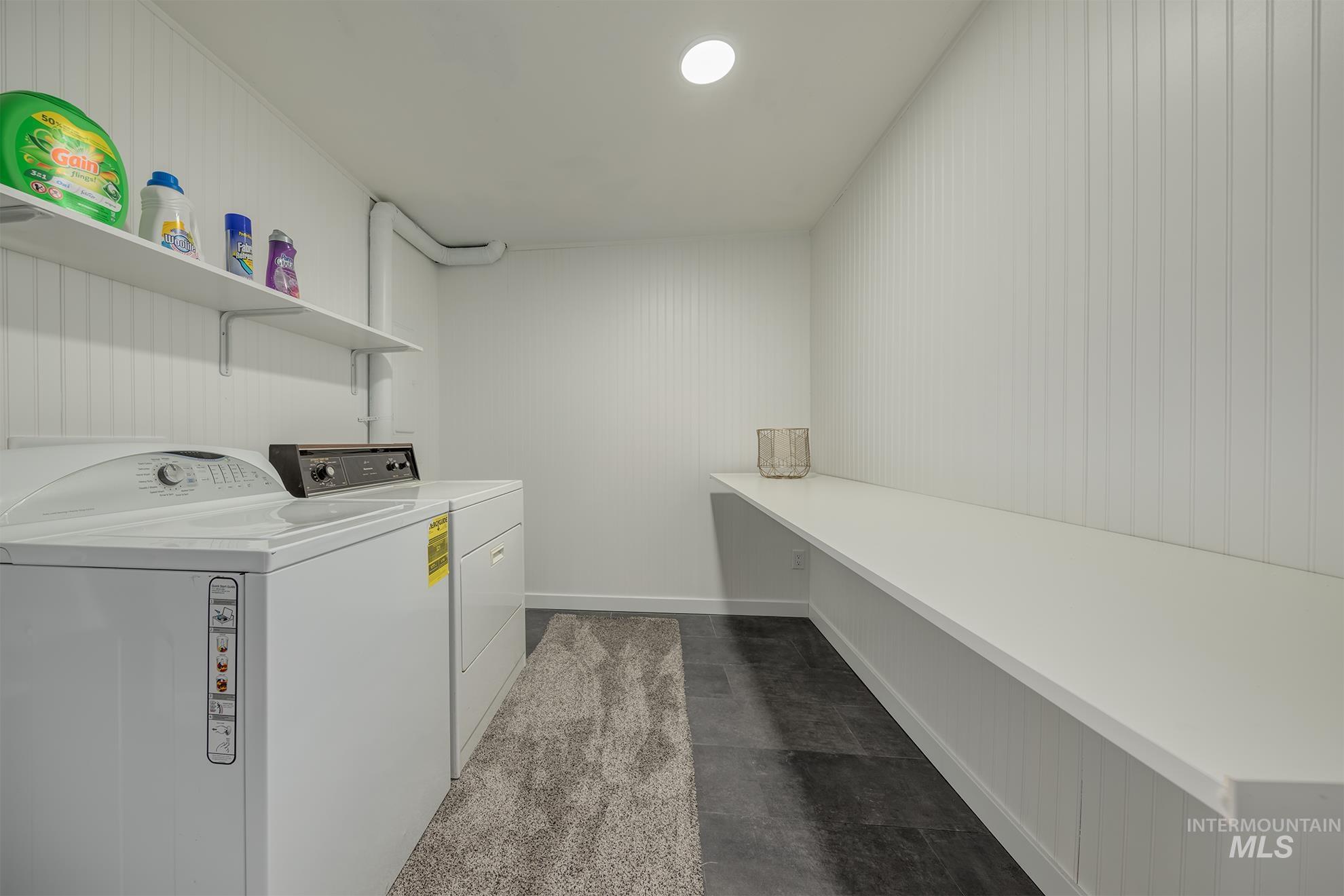 Laundry room featuring beadboard paneling, built-in shelving, and dark-toned flooring