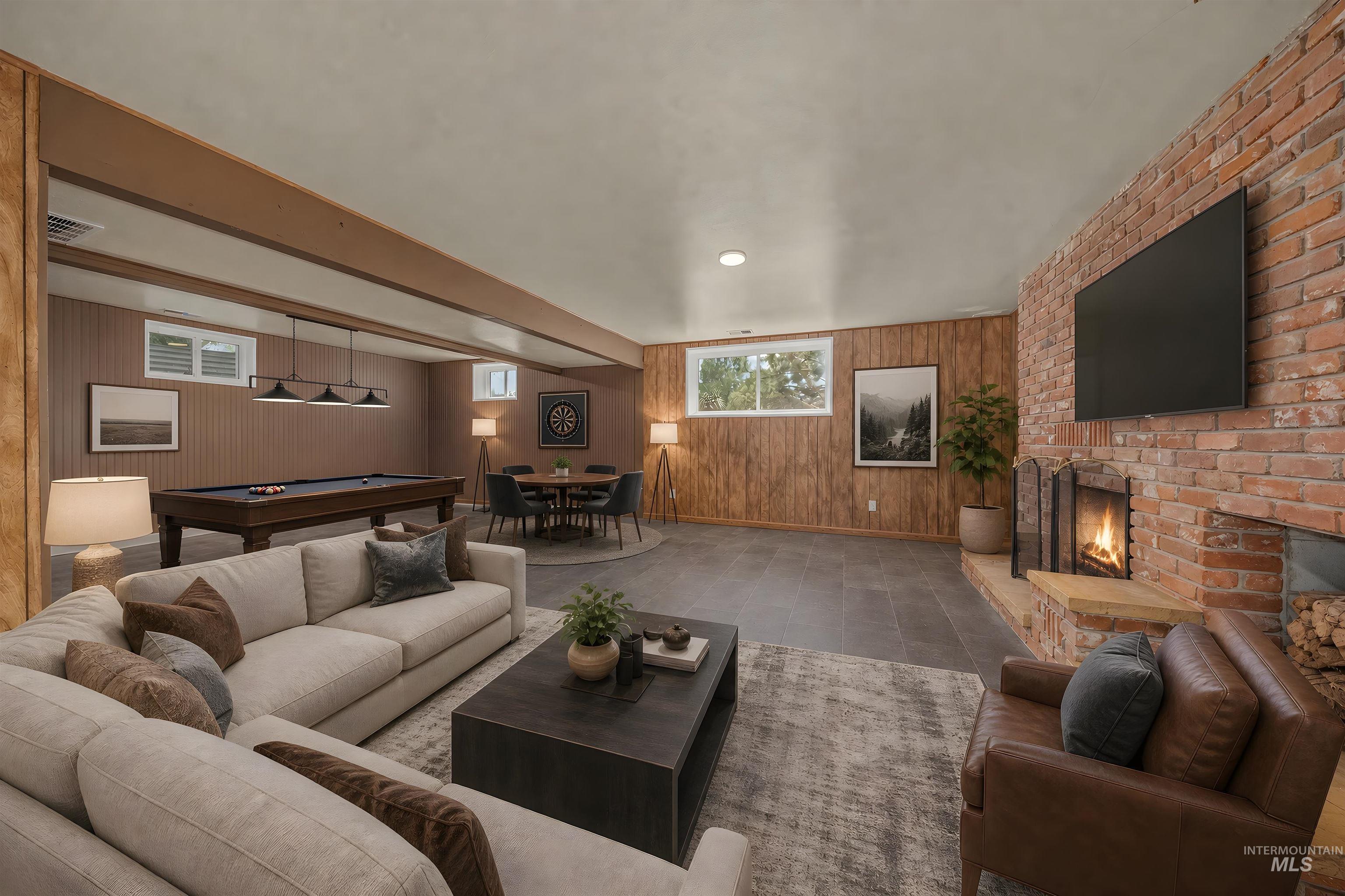 Spacious recreation room featuring a brick fireplace, wood-finish paneling, and tile flooring
