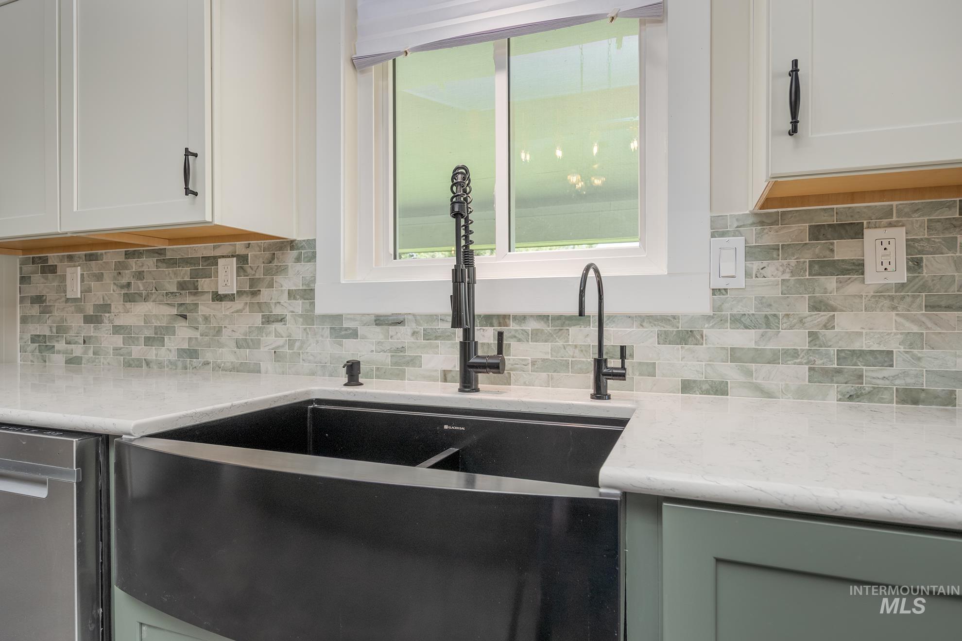 Modern kitchen sink area featuring a black apron-front sink and matte black fixtures