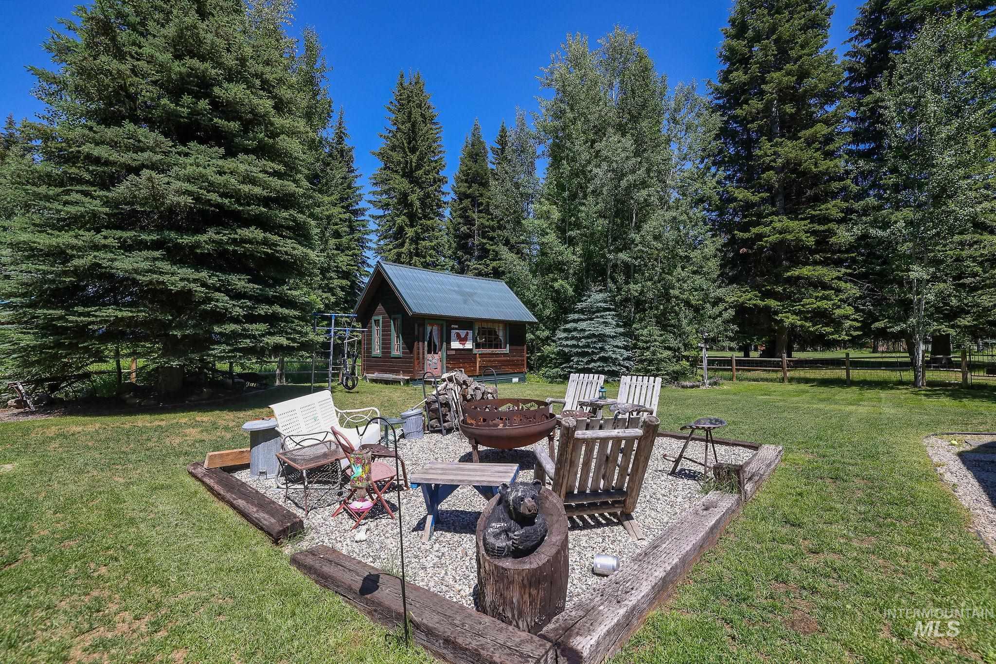 Expansive outdoor area featuring a central fire pit with a gravel base and wood-beam borders