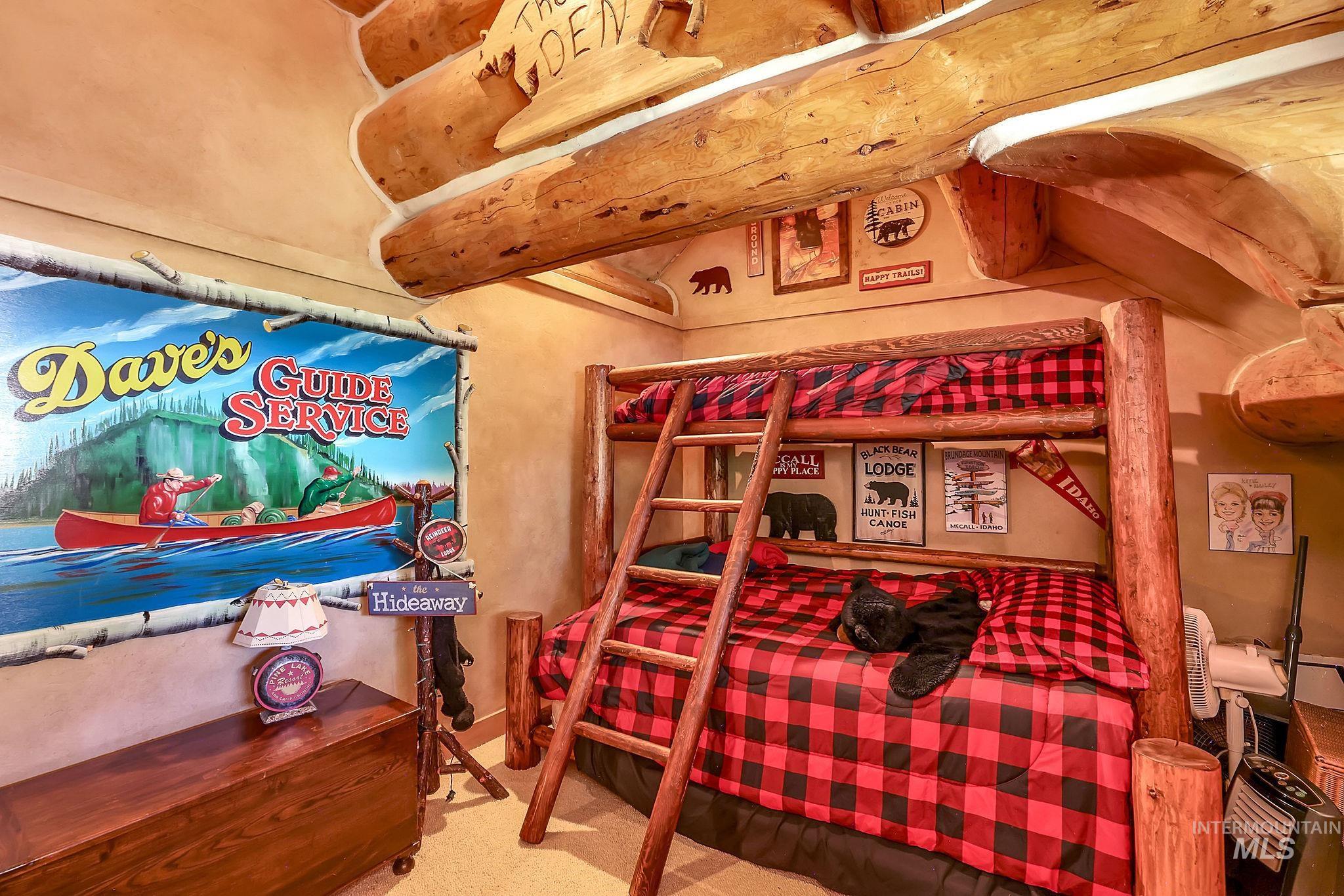 Log cabin-style bedroom featuring prominent exposed log beams and a built-in log bunk bed with an integrated ladder