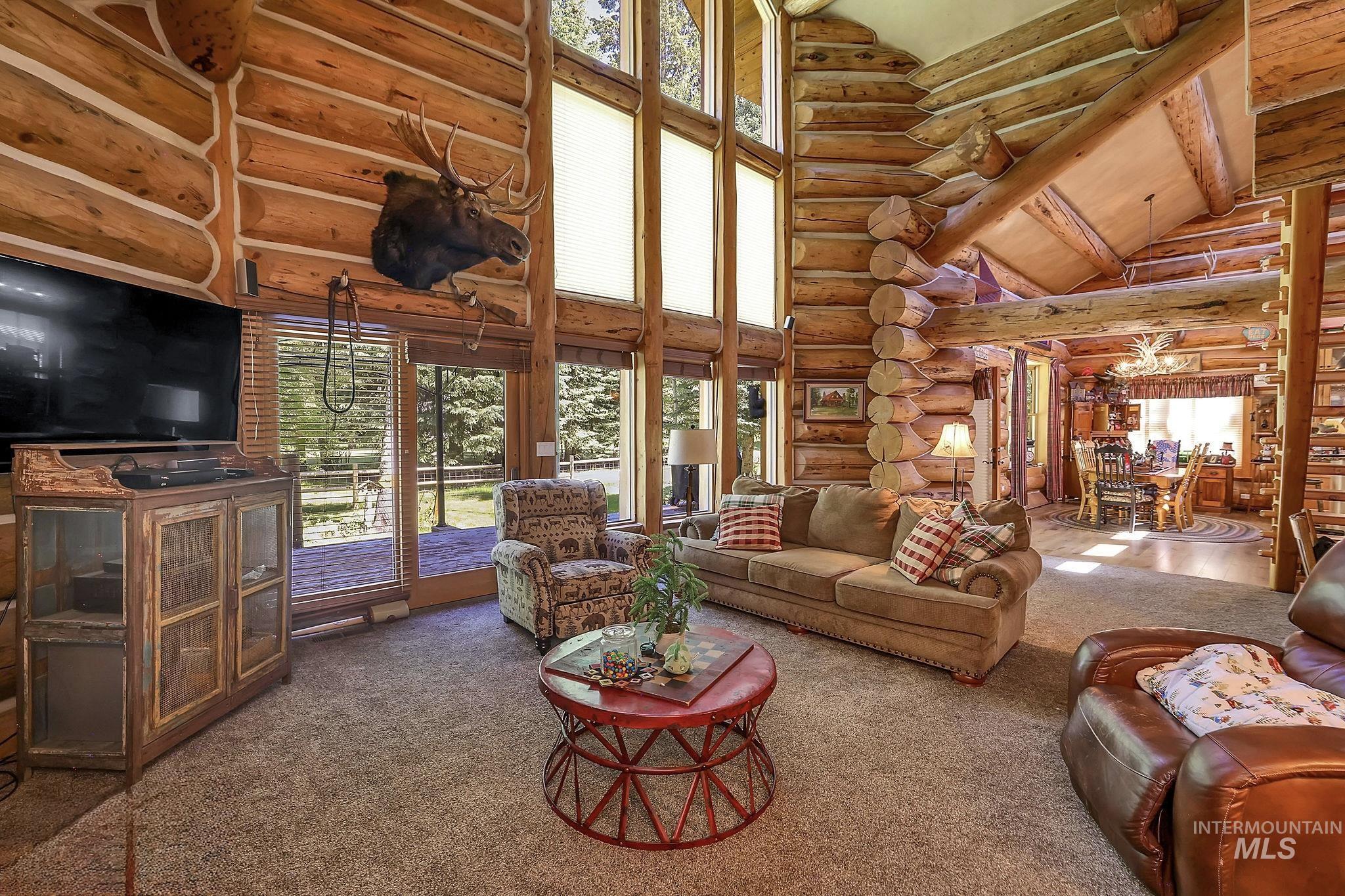 Two-story living area featuring log construction and exposed beam ceiling