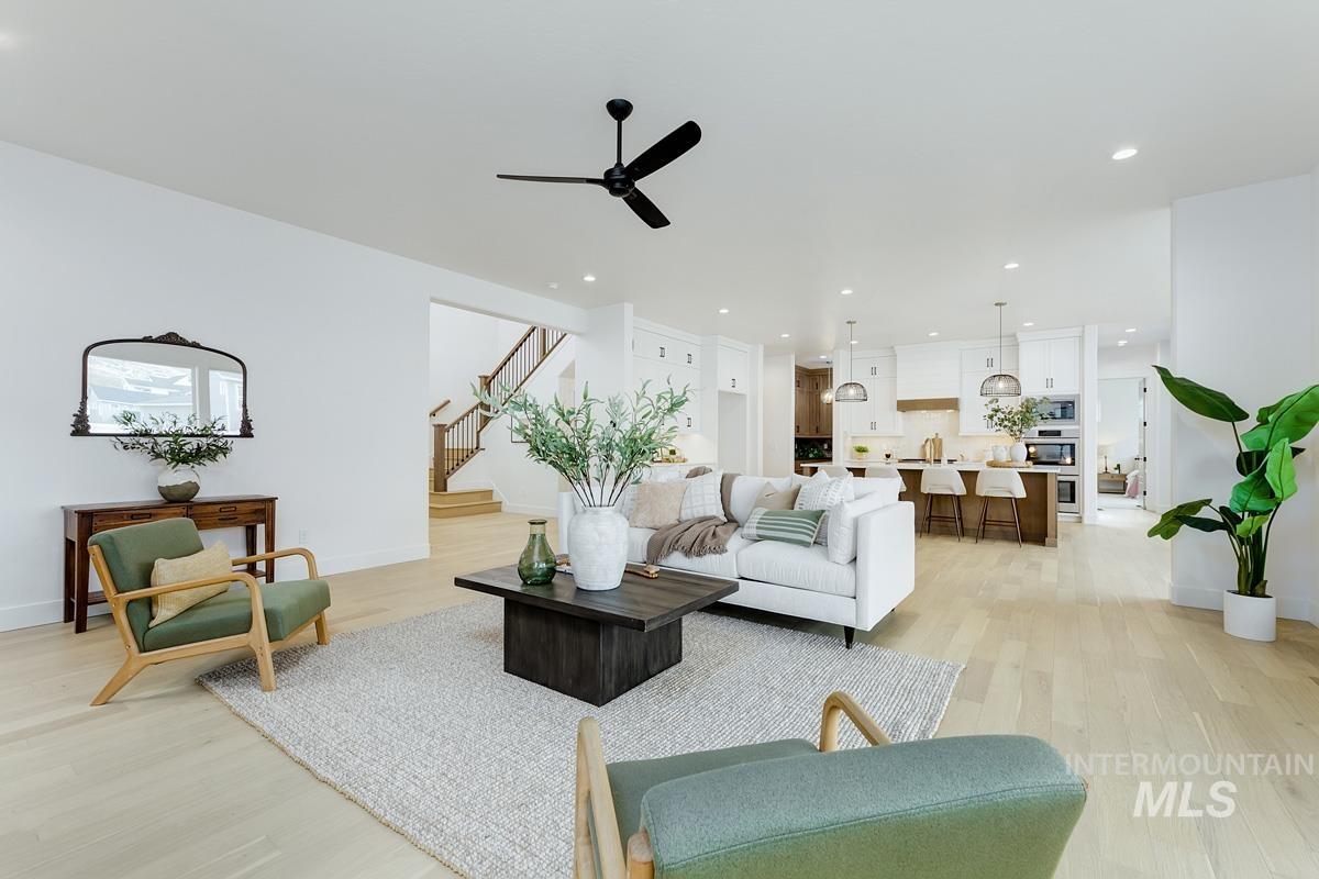 Living room featuring light wood-style flooring, a ceiling fan, stairway, and recessed lighting