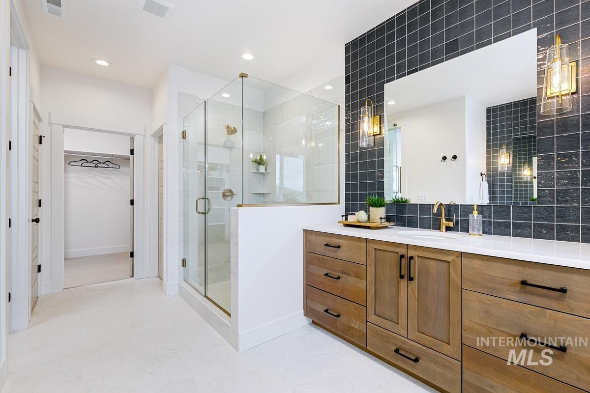 Bathroom with a spacious closet, vanity, a stall shower, tasteful backsplash, and light tile patterned floors