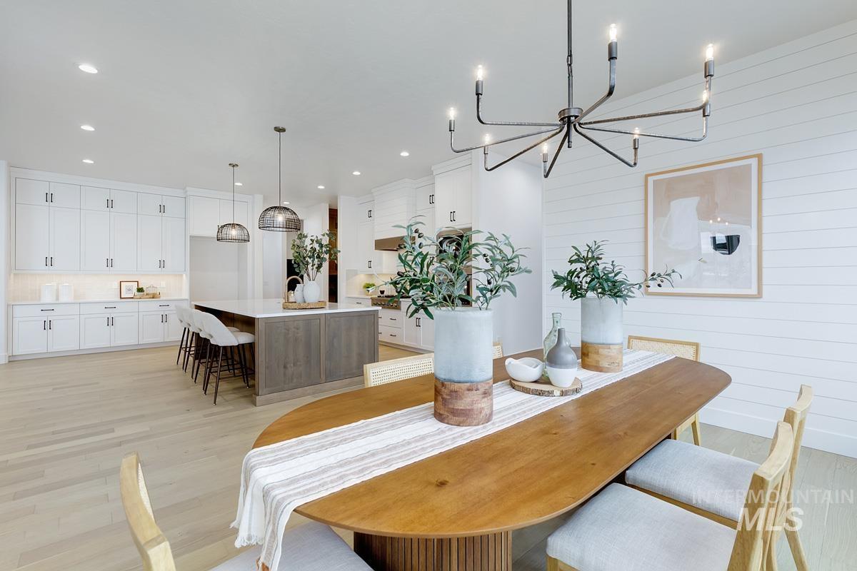 Dining room with light wood finished floors, a chandelier, recessed lighting, and wood walls