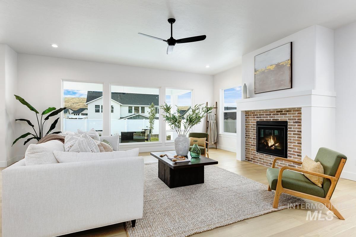 Living area with plenty of natural light, light wood-style flooring, a brick fireplace, a ceiling fan, and recessed lighting