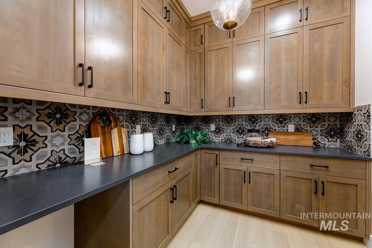Kitchen with tasteful backsplash, brown cabinets, hanging light fixtures, and light wood-type flooring