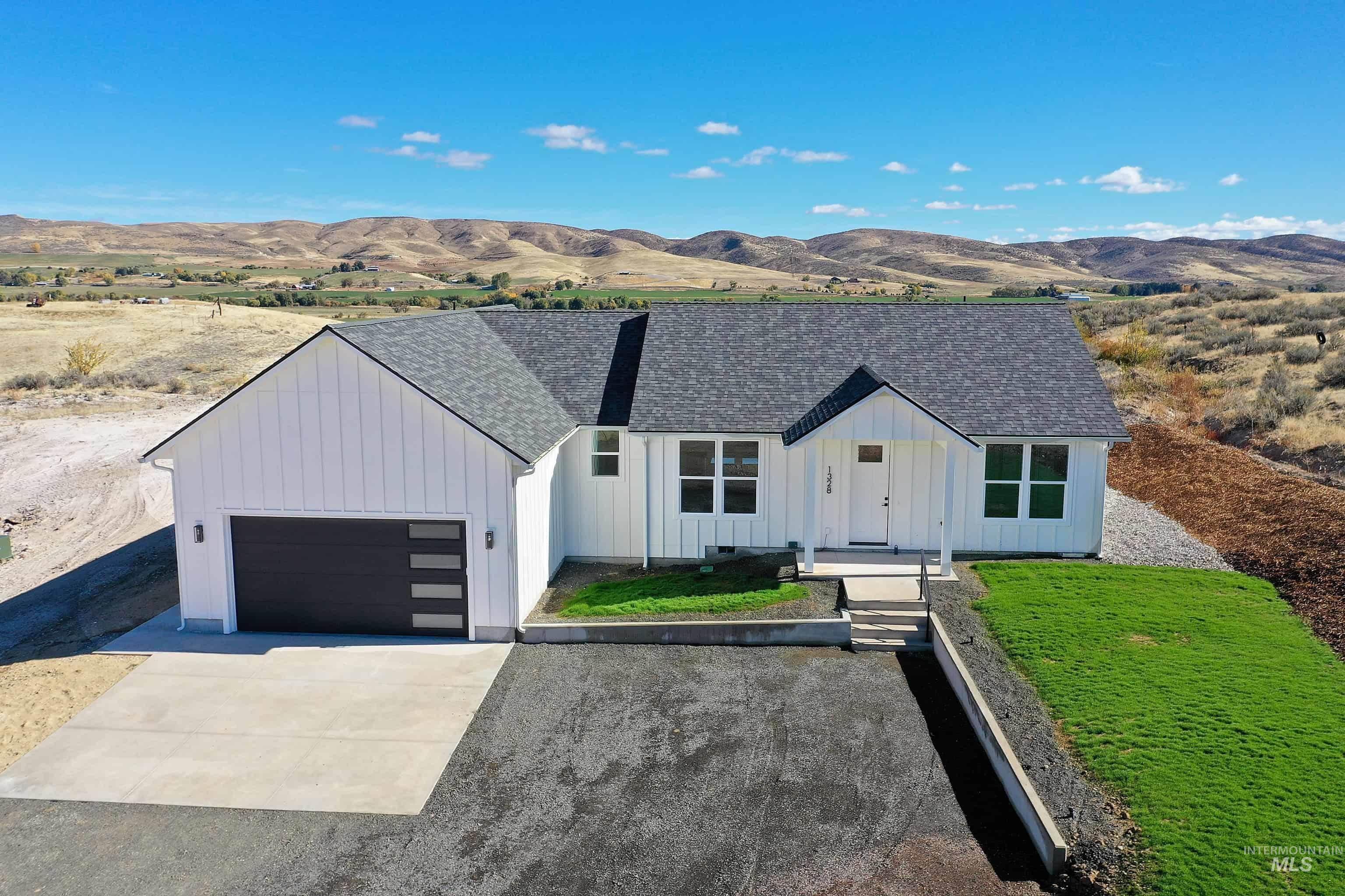 Modern inspired farmhouse with board and batten siding, a mountain view, a shingled roof, concrete driveway, and a garage
