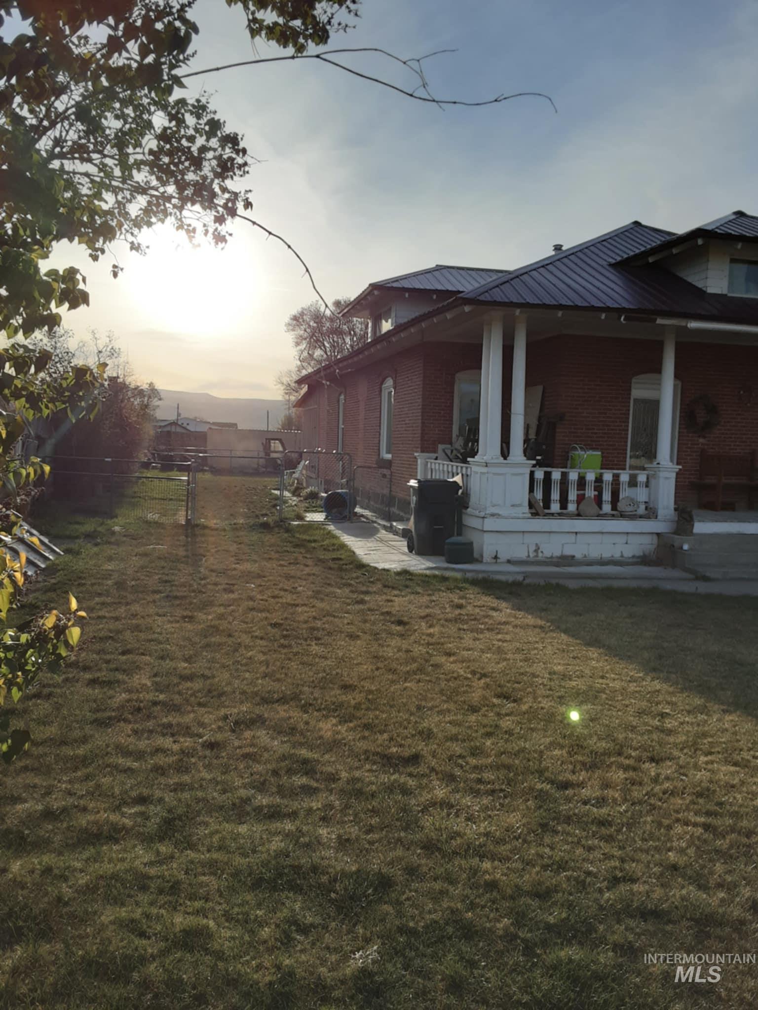 Property exterior at dusk with a patio, brick siding, and a metal roof