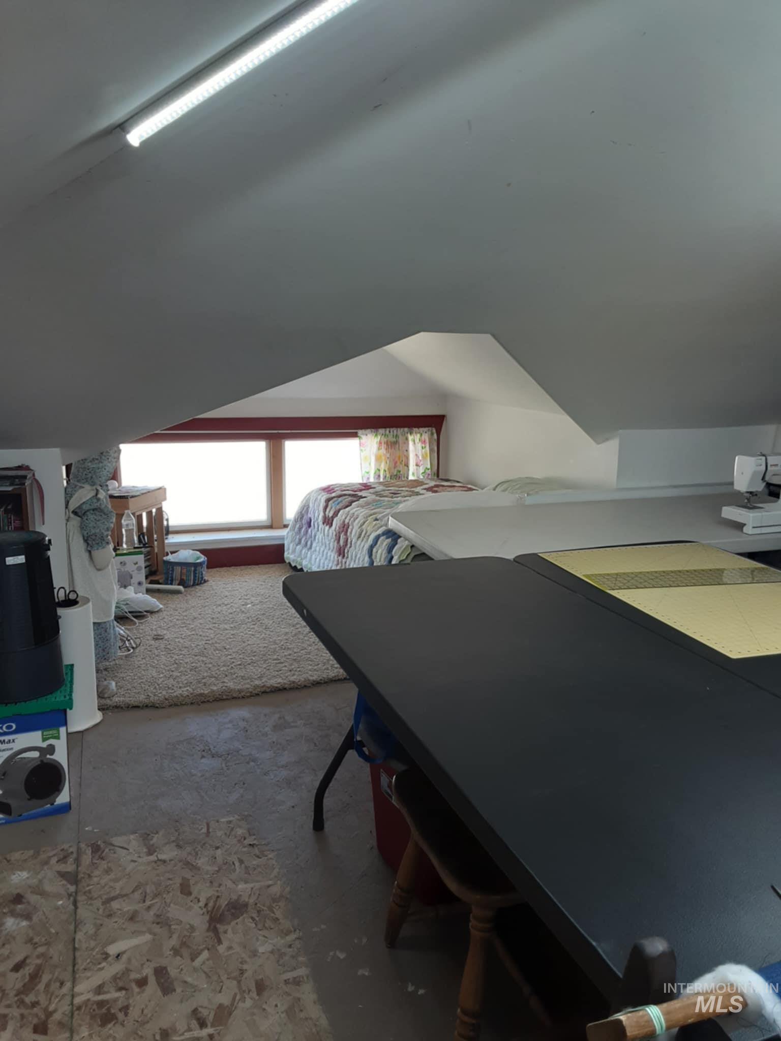 Bedroom featuring lofted ceiling and unfinished concrete floors