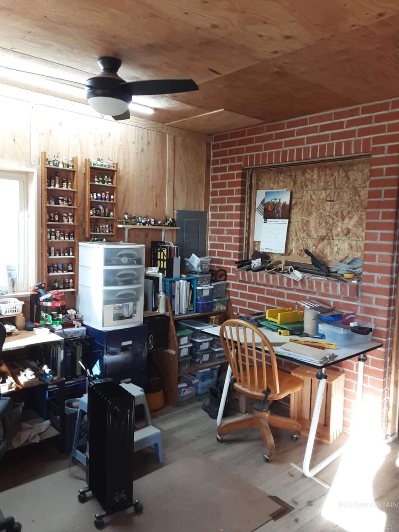 Office with light wood-type flooring, wooden walls, electric panel, ceiling fan, and wood ceiling