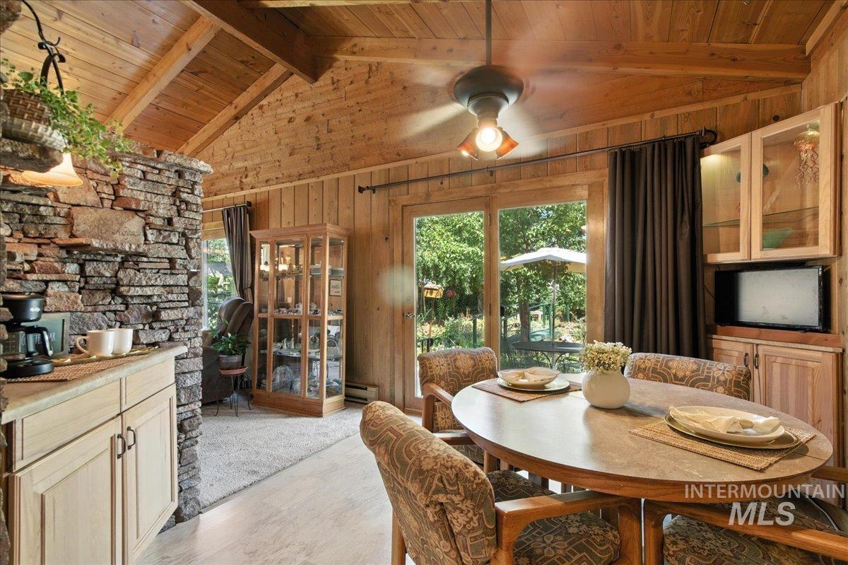 Dining area with wooden ceiling, light wood finished floors, a baseboard radiator, and wood walls