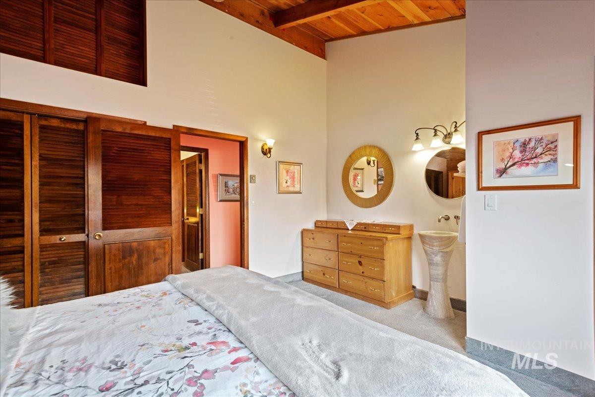 Bedroom featuring high vaulted ceiling, a wood ceiling with exposed beams, and carpet floors