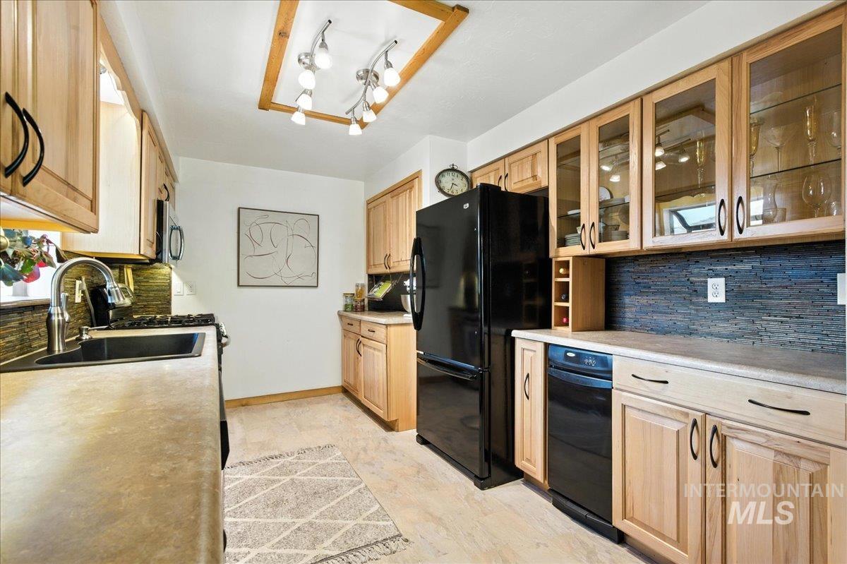 Kitchen featuring decorative backsplash, freestanding refrigerator, and light brown cabinetry