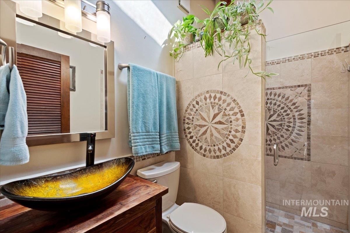 Bathroom featuring tiled shower, vanity, and tile walls