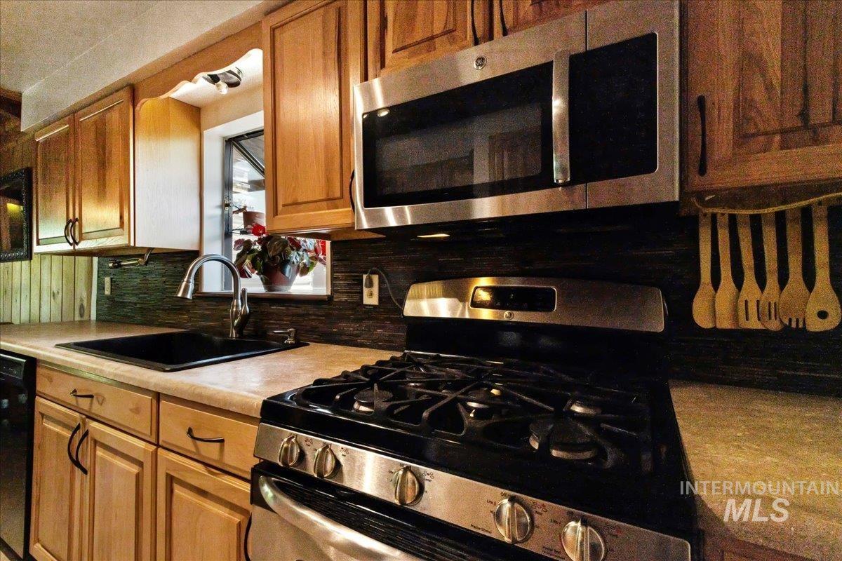 Kitchen with appliances with stainless steel finishes, tasteful backsplash, light countertops, and brown cabinets