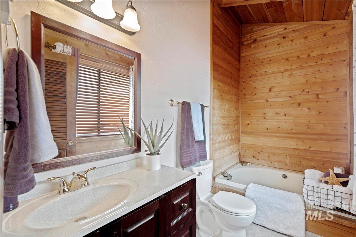 Full bathroom with a bathtub, vanity, and wood walls