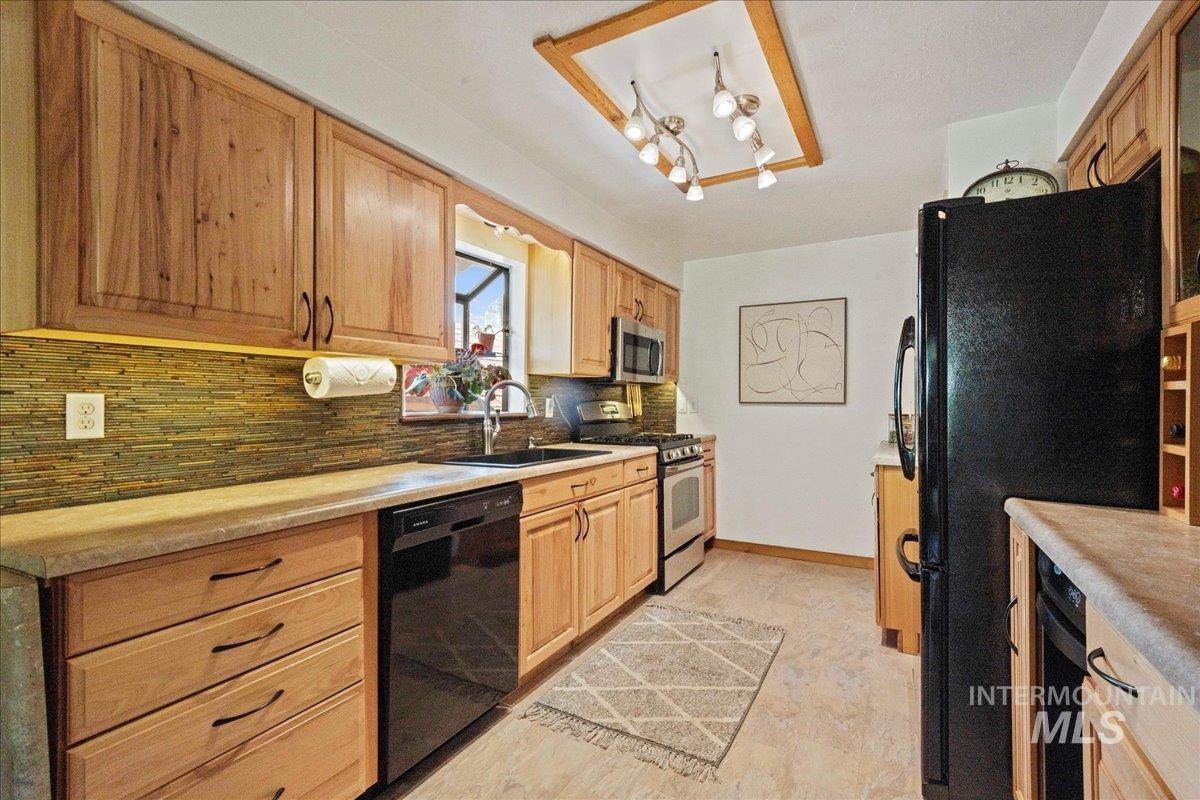Kitchen featuring black appliances, decorative backsplash, and light countertops