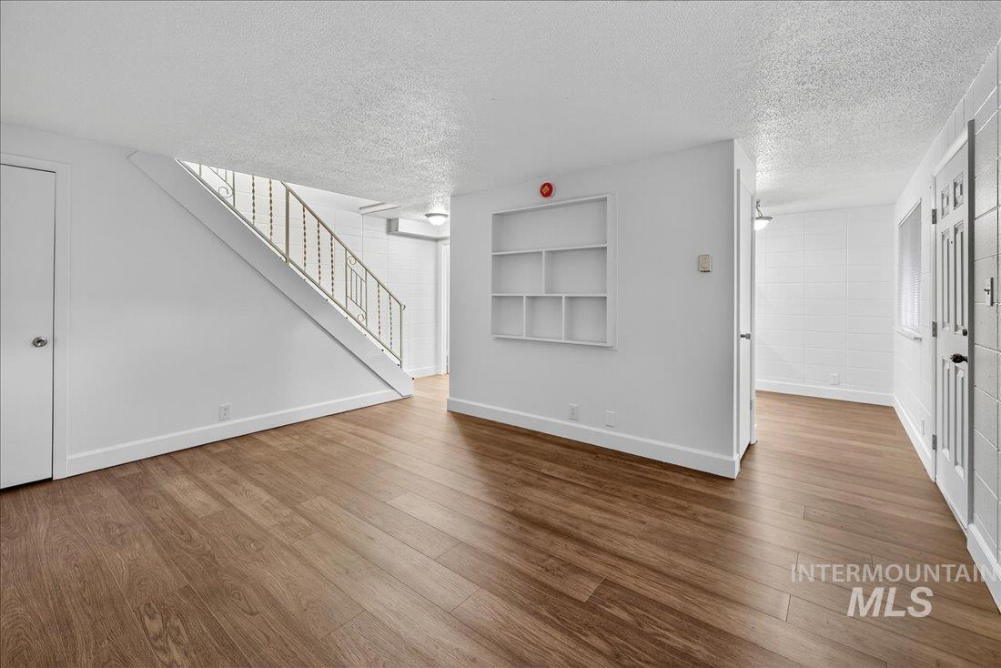 Unfurnished living room with wood finished floors, stairway, a textured ceiling, and built in features