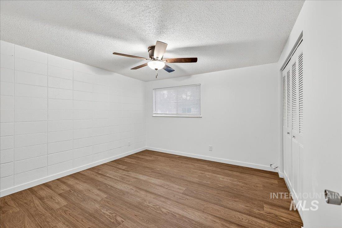 Unfurnished bedroom with wood finished floors, a textured ceiling, a closet, and ceiling fan