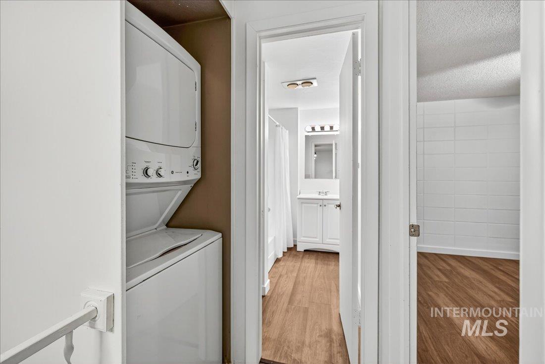 Washroom with light wood-style flooring, stacked washer / dryer, and a textured ceiling
