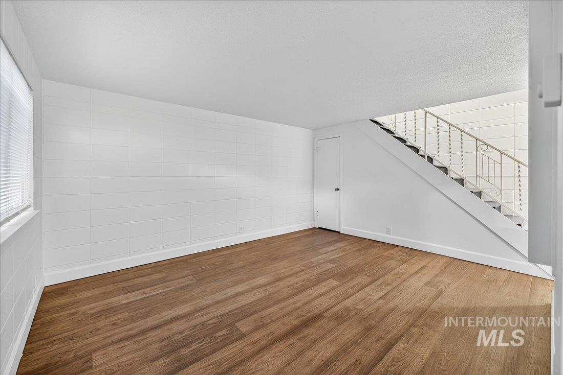 Unfurnished living room featuring wood finished floors and stairs