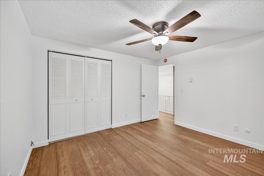 Unfurnished bedroom featuring light wood-style floors, a closet, a ceiling fan, and a textured ceiling