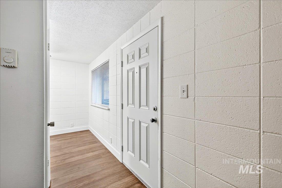 Hall with light wood-style flooring and a textured ceiling