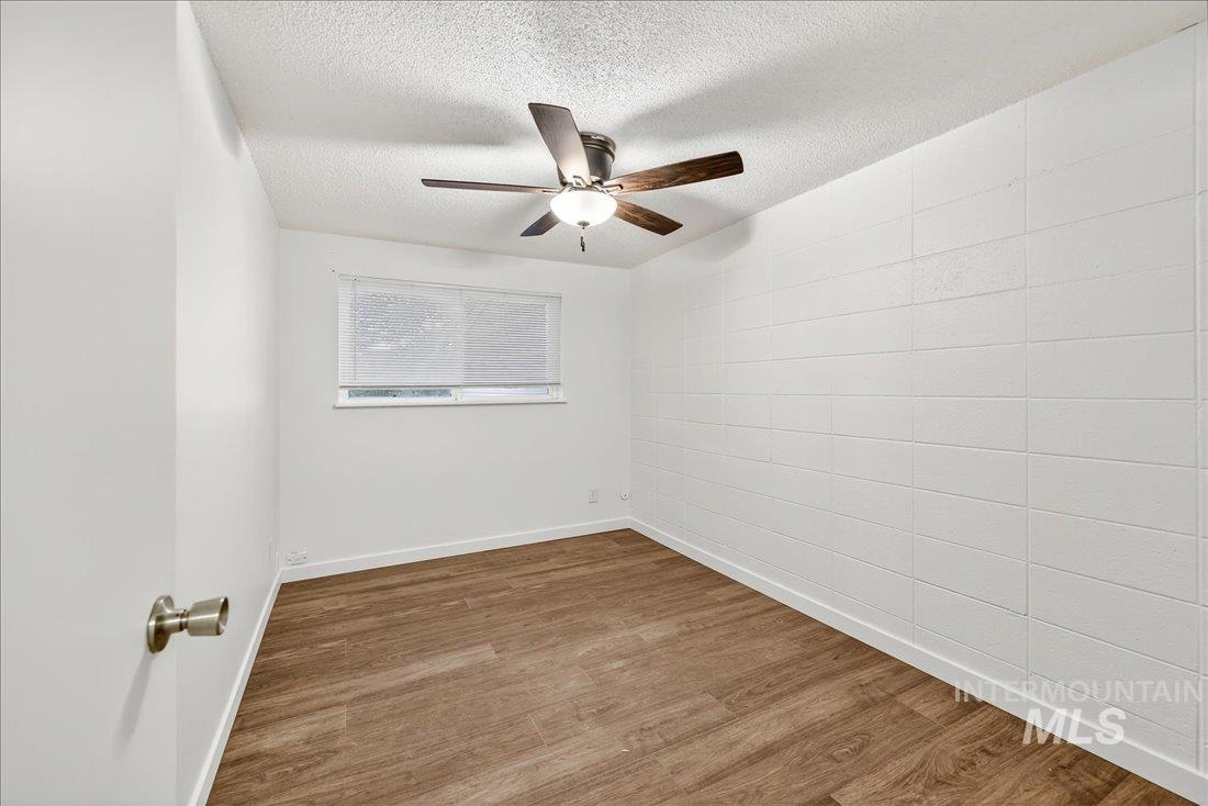 Spare room featuring wood finished floors, a textured ceiling, and ceiling fan
