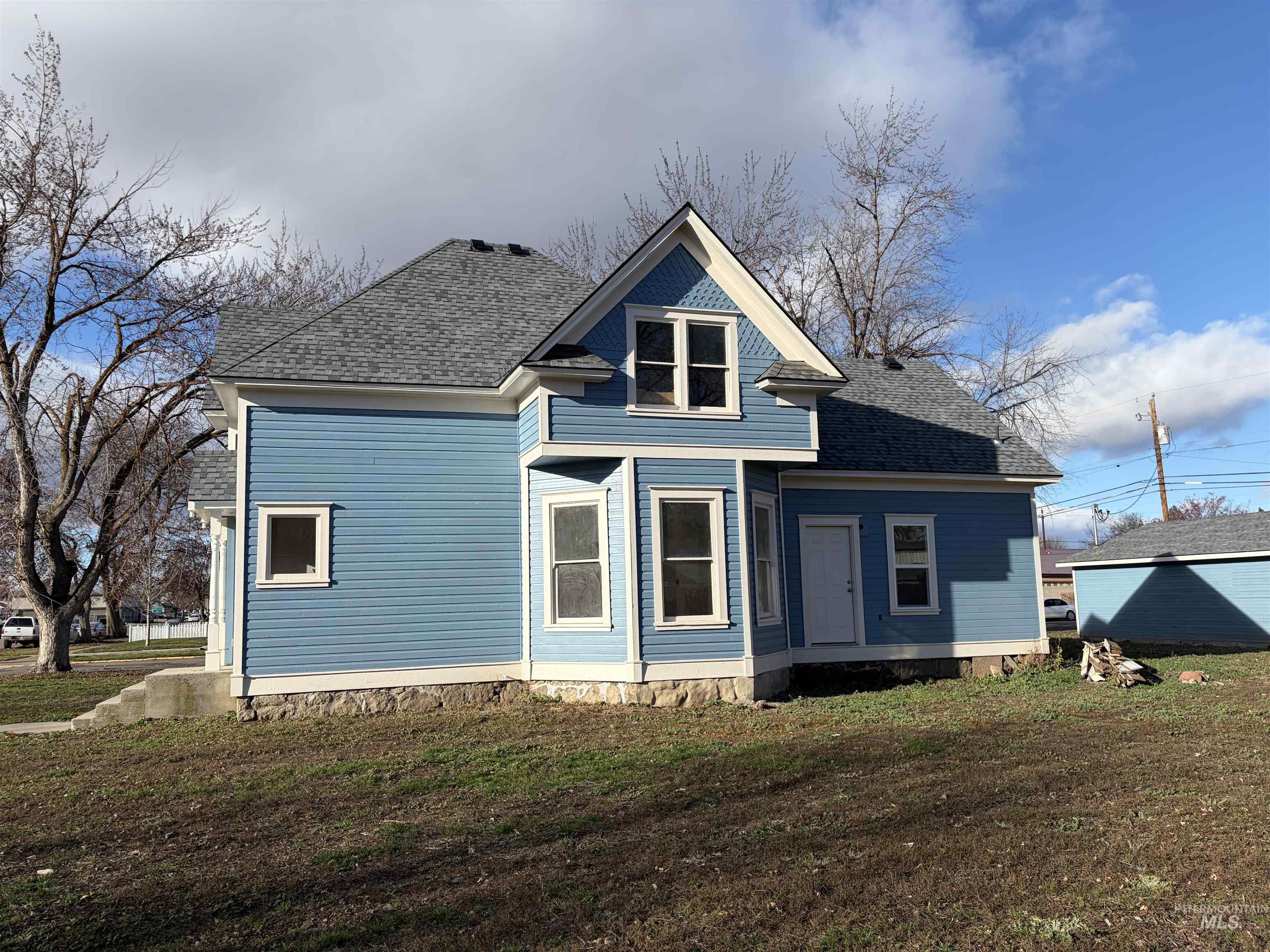 Rear view of property featuring a shingled roof and a yard