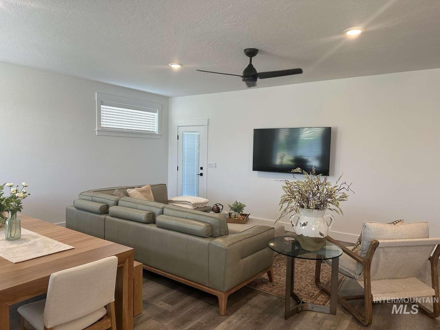 Living area featuring wood finished floors, a textured ceiling, and a ceiling fan