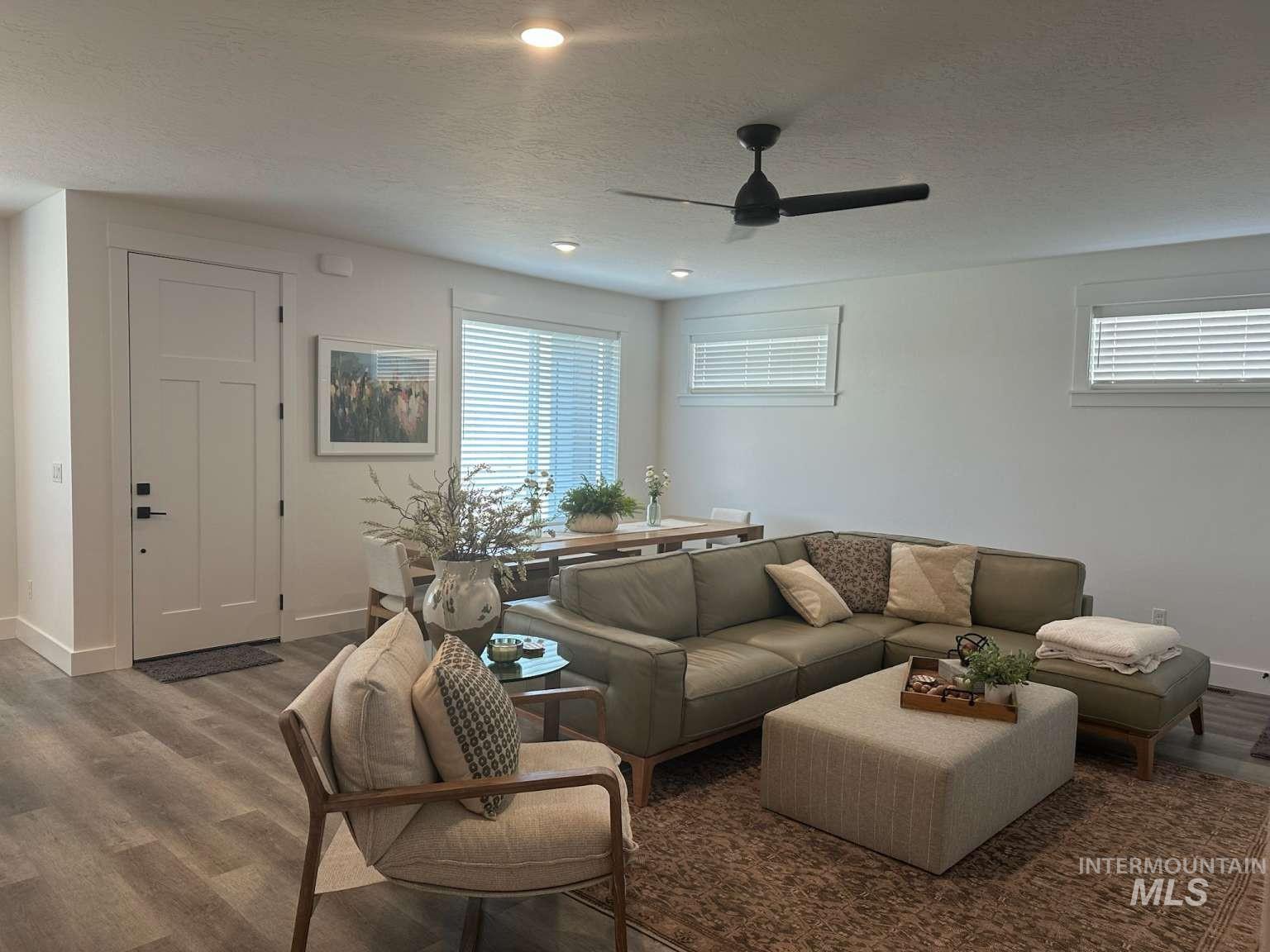 Living room with a textured ceiling, healthy amount of natural light, wood finished floors, recessed lighting, and ceiling fan